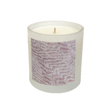 A wax candle in a white container with artwork by Damien Coulthard on the front.