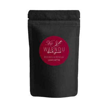 A black packet with a round burgundy sticker on the front with the text 'Warndu Feel Good Rooibos and Rosella'.