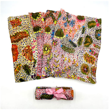 A baby swaddle is fanned out and printed with artwork by Olivia Wilson. There is another one rolled up in front.