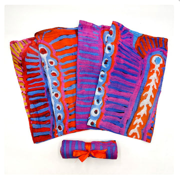 A baby swaddle is fanned out and printed with artwork by Murdie Nampijinpa Morris. There is another one rolled up in front.