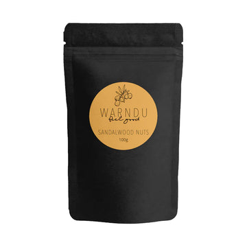 A black packet with a yellow orange round label on the front with the text 'Warndu Feel Good Sandalwood Nuts'.