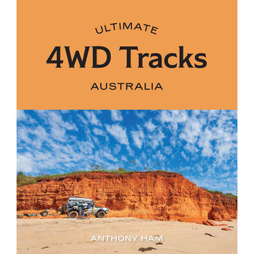 'Ultimate 4WD Tracks Australia' book cover featuring a photo of a 4WD with a person sitting on a chair on a beach with a large rock and cloudy blue sky in the background.