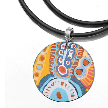 A round pendant printed with artwork by Murdie Morris on a black rubber cord.