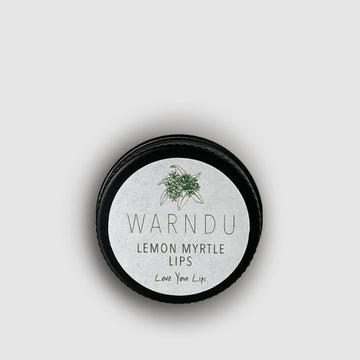 A small round black container with the text 'Warndu Lemon Myrtle Lips Love your Lips' written on the front.