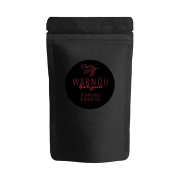 A black packet with a black round label on the front and the text 'Warndu Feel Good Quandong & Black Tea' written in red.