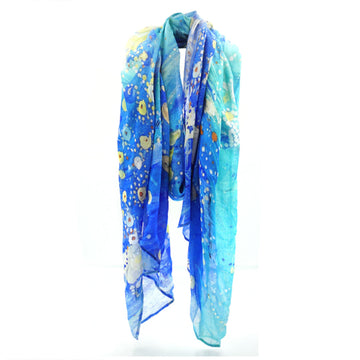 A cotton scarf is laid like it was wrapped around a neck. The scarf features artwork by Stephen Jupurrula Nelson in blue and yellow.