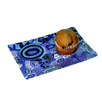 A small rectangle plate pictured printed with artwork by Theo Hudson and with a muffin on top.