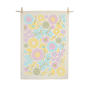A tea towel featuring a floral print by Claire Ishino is hanging from a rope with two pegs holding it in place.