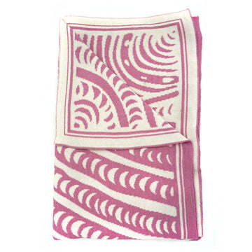 A pink and white baby blanket is folded up with the corner folded over to show the back.