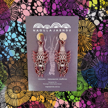 A pair of drop stud earrings with a gold circle top and resin crayfish attached on a card over a colourful patterned background.