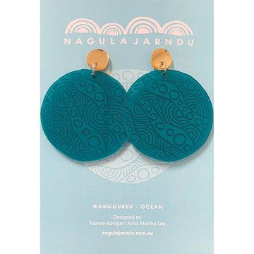 A pair of stud drop earrings with a small gold circle stud attached to a large blue acrylic engraved circle on a light blue card.