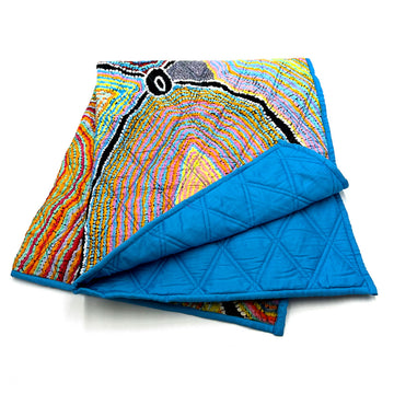 A folded up quilted baby blanket printed with artwork by Liddy Walker on the top and blue on the bottom.