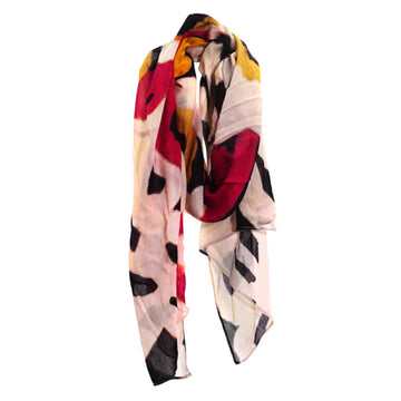 A cotton scarf is laid like it was wrapped around a neck. The scarf features artwork by Anmanari Brown in red, yellow and white.