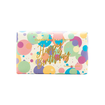 A bar of soap wrapped in packaging printed with confetti and the text 'Happy Birthday' in gold.