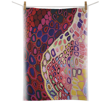 A cotton tea towel printed with artwork by Amanda Jane Gabori is hanging from a white cord with pegs.