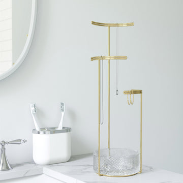A brass jewellery stand with three levels and a silver mesh base.