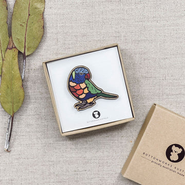 A wooden brooch in the shape of a lorikeet and painted in rainbow colours.