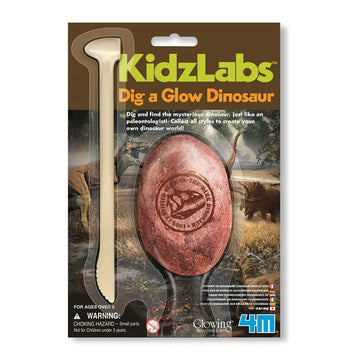 Packaging for 'Dig a Glow Dinosaur' featuring an egg shaped fossil and a digging tool wrapped in plastic on card. The card has images of dinosaurs.