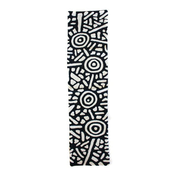 A black and white table runner is laying flat and features artwork by Anthea Granites.