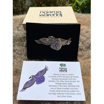 An enamel pin the shape of an illustrated crow in blue and black.