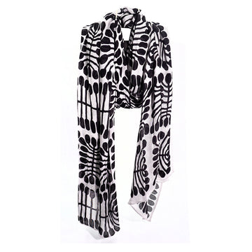 A black and white cotton scarf printed with artwork by Mitjili Napurrula laid out like its wrapped around a neck.