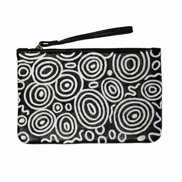 Black Leather clutch 14cm x 22.5cm, strap, stainless steel zipper, white embroidery. Artwork by Nelly Patterson. Black background, white concentric circles, symbols. Depicts camp sites from the seven sisters story.