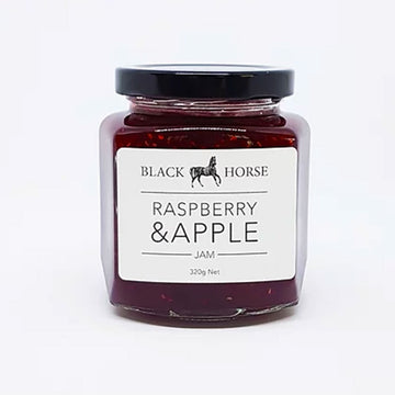 A clear jar with a white product label and black lid. The product label says 'Black horse Raspberry & Apple Jam with an image of a horse at the top. The jam can be seen through the jar.