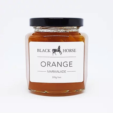 A clear jar with a black lid and white product label. The label says 'Black Horse Orange Marmalade' with an image of a horse. The marmalade can be seen through the jar.