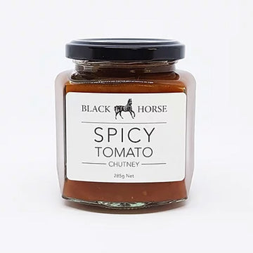 A clear jar with a black lid and white product label. The label says 'Black Horse Spicy Tomato Chutney' with an image of a horse. The chutney can be seen through the jar.