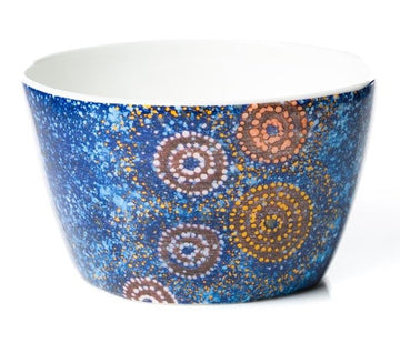 Bright and colourful Fine Bone China nut bowl featuring blue background with red, white, and orange dot art circles.  Artwork by Warlukurlangu Artist Alma Granites. Glossy white glaze inside.