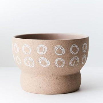 A shaped pot planter in a sand colour with white circles.