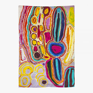 A silk scarf laid out featuring artwork by Jakayu Biljabu in pinks, blues and yellow.