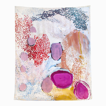 A silk scarf is laid out featuring artwork by Mulyatingki Marney with pink circles and red, blue and orange spots on a white background.