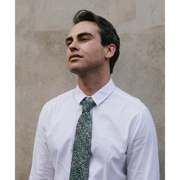 A black and green tie featuring artwork by Molly Miller.