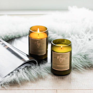 A candle made from a wine bottle with a cork lid lying down surrounded by cut in half pears.