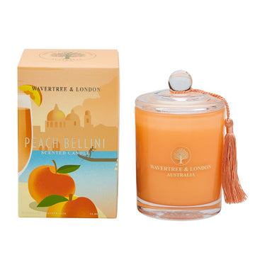 Candle by Wavertree and London.  Peach glass votive with clear glass lid packed in an orange box with a picture of a beach a boat two peaches and a peach bellini.