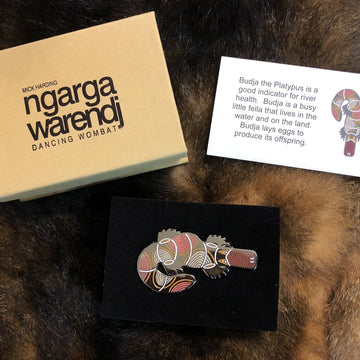 Enamel on metal brown, black and white platypus brooch by Ngarga-warendj. 