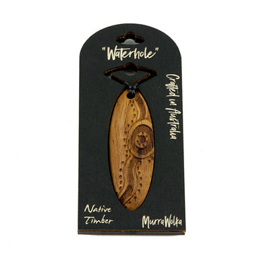 Wooden necklace with carvings pictured inside cardboard packaging. The packaging includes the words 'Waterhole' 'Crafted in Australia' 'Native Timber' and 'MurraWolka'.