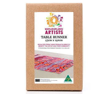 Poly cotton table runner 45cm x 140cm, made in Australia. Red, pink, orange, purple artwork by Murdie Morris from Warlukurlangu Artists. Cardboard gift box, with artwork image and text.