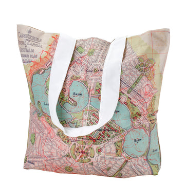 A tote bag featuring a coloured map of Canberra city printed on the front with a white strap folded over.