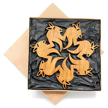 A wooden trivet made from seven kangaroos cut out with their foot touching the kangaroo in front's back to make one piece.