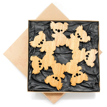 A wooden trivet featuring koalas cut out and touching to form one shape.