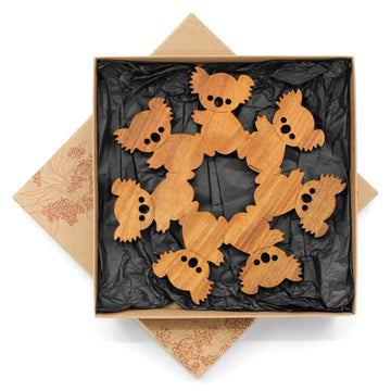 A wooden trivet featuring cut out koalas sitting next to each other to form one shape.