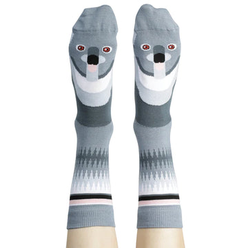 A pair of legs wearing grey knee high socks printed with a koala's face.